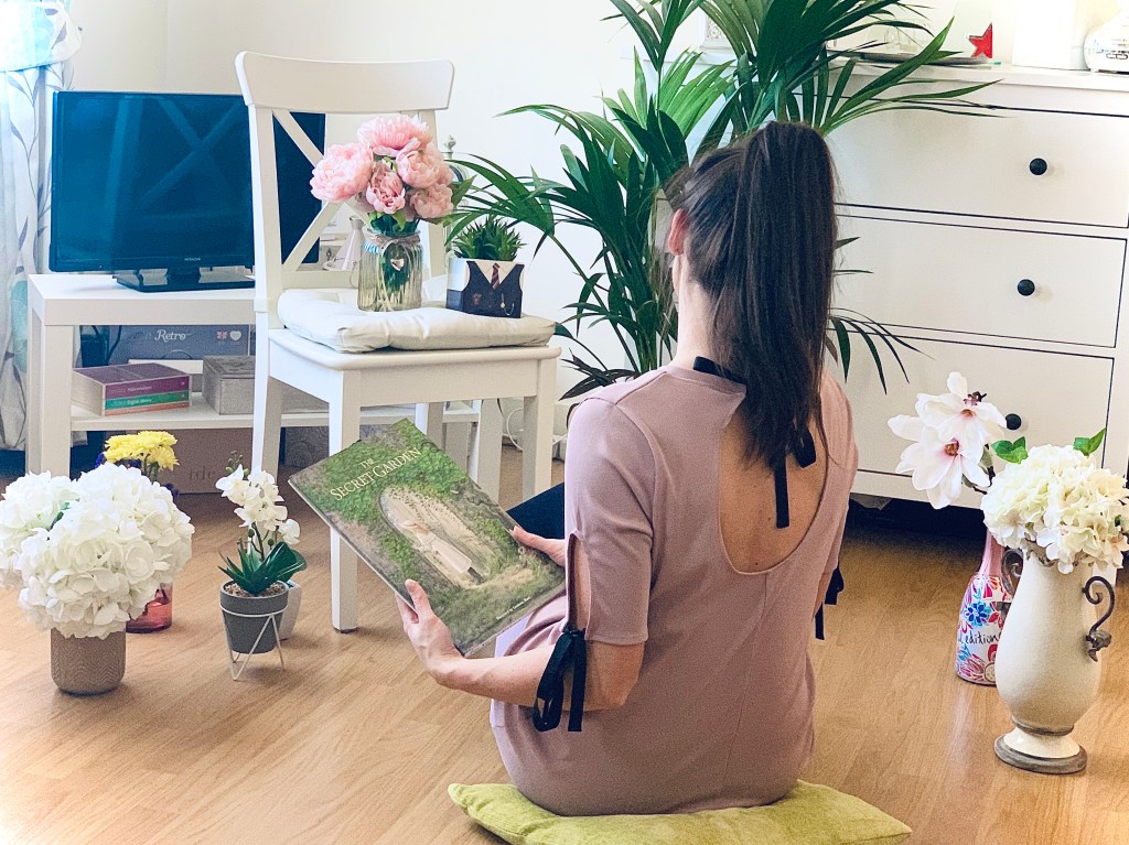 Girl reading the book "The Secret Garden" to her flowers and plants.